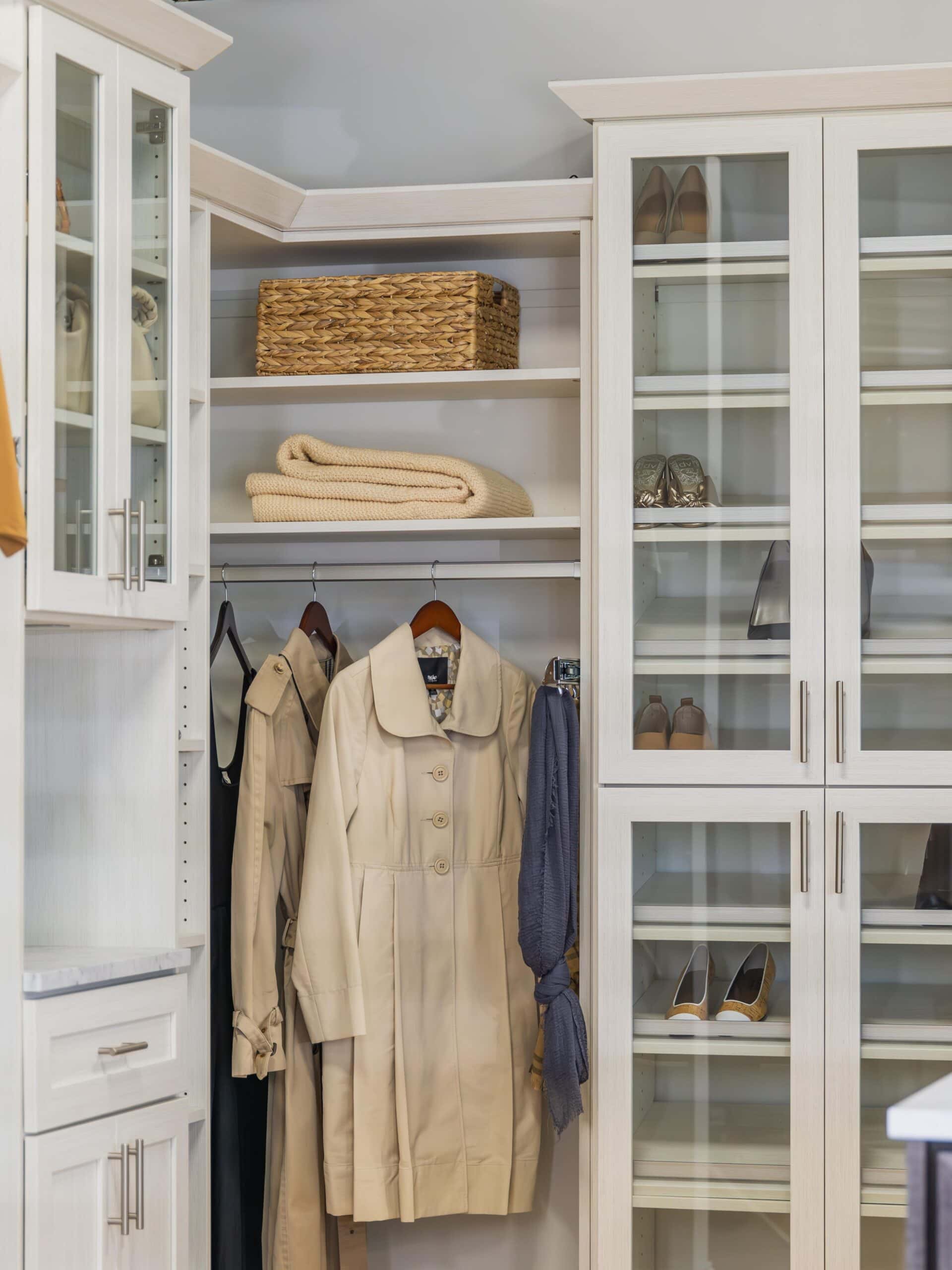 walk-in closet with hanging coats and shoe cabinet with glass doors