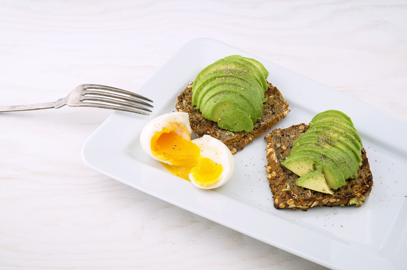  Egg and Avocado breakfast toast sitting on a white plate