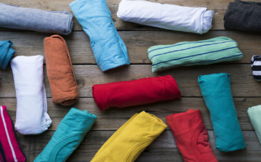 close up of rolled colorful clothes on wooden table background