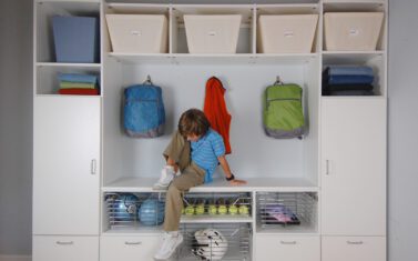 boy sitting on a custom mudroom entry cabinet